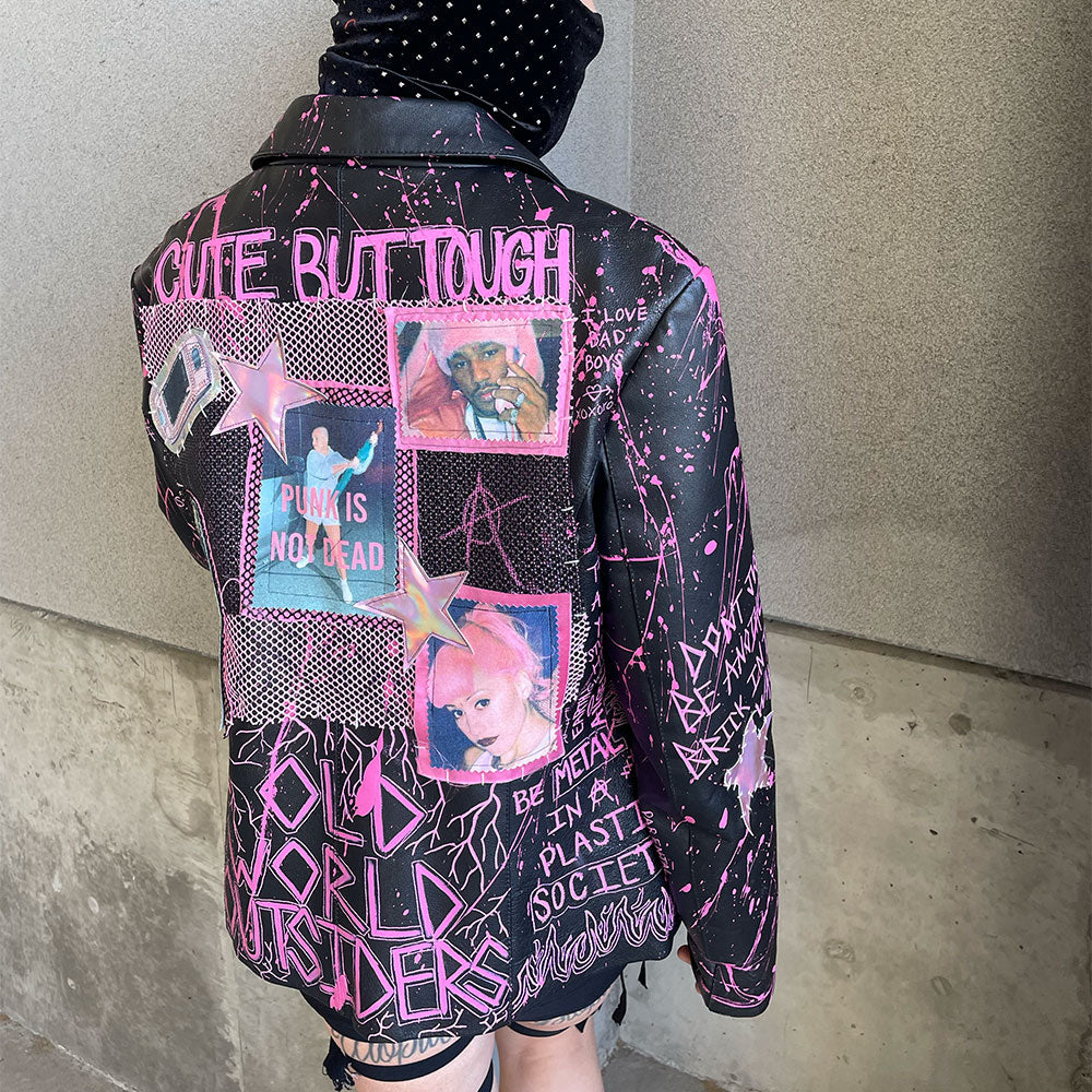 Person wearing a black jacket with pink text and graphics against a plain background