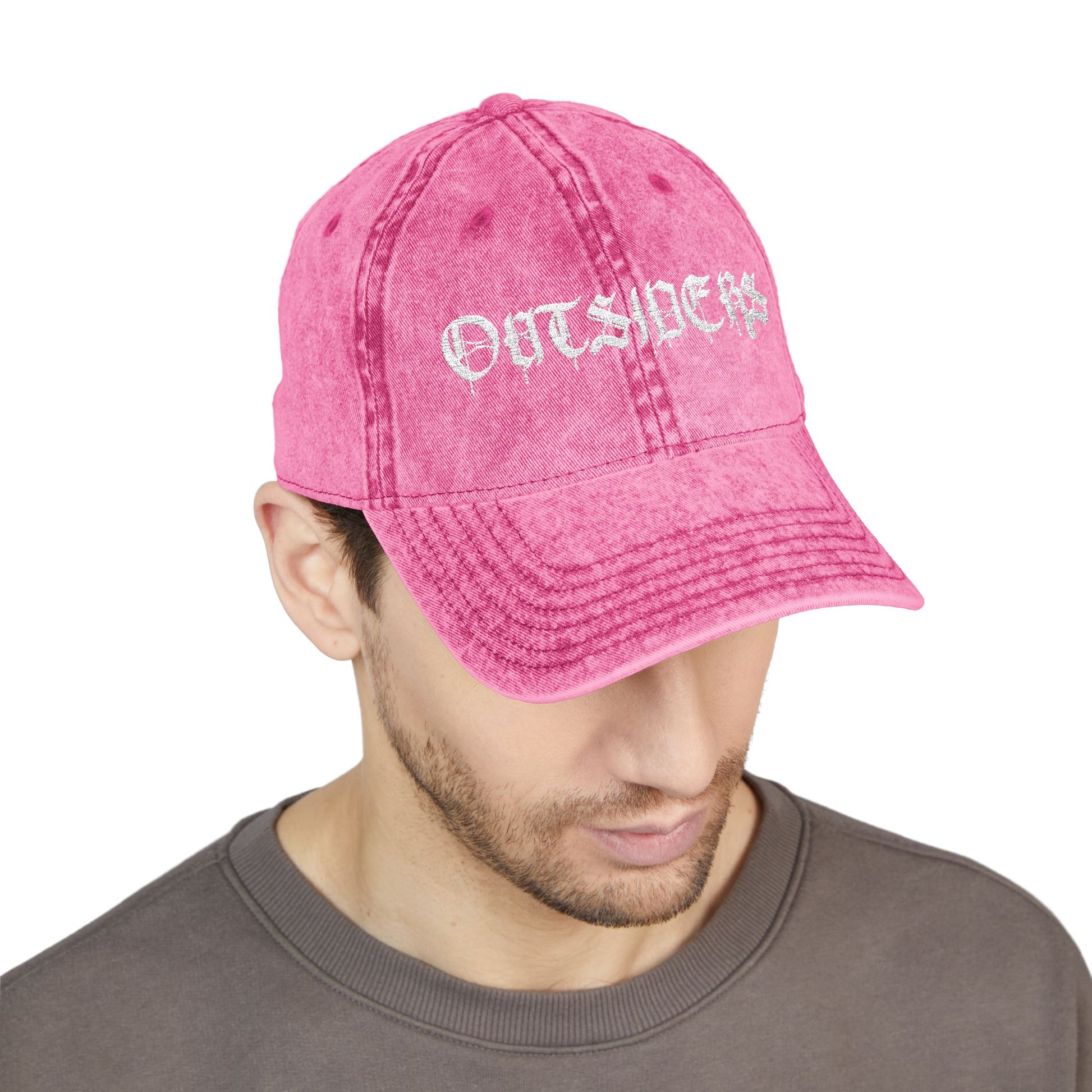 Pink cap with 'OUTSIDERS' text worn by a person on a white background