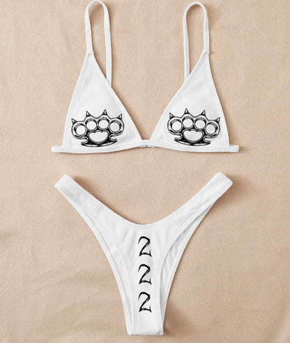 White bikini set with brass knuckles design on beige background
