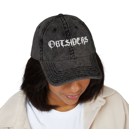 Person wearing a black denim cap with 'OUTSIDERS' text on a white background