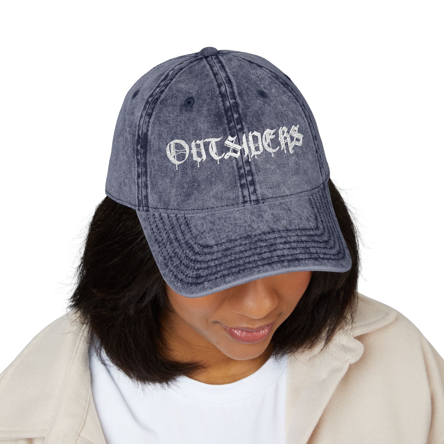 Person wearing a denim cap with 'OUTSIDERS' text on a white background