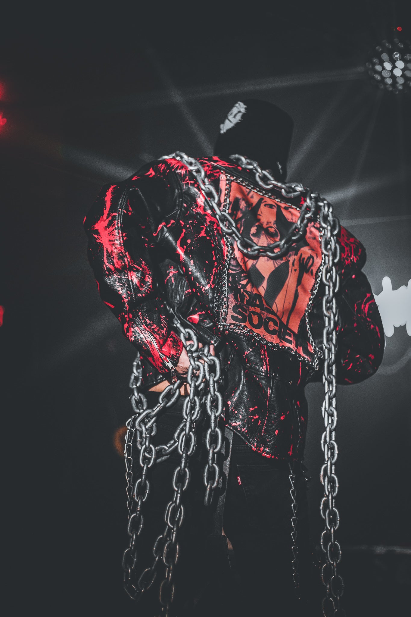 Black leather jacket with chains and red accents on a dark background