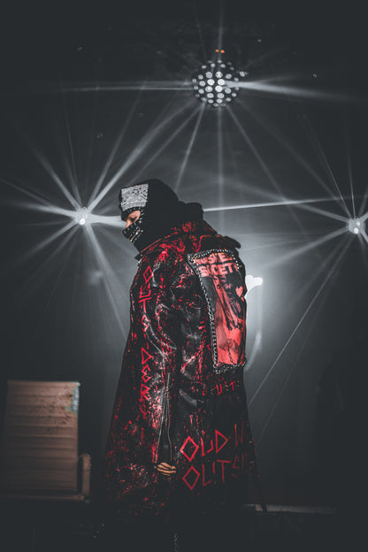 Person wearing a black and red coat with text, standing in a dark room with disco ball lights.
