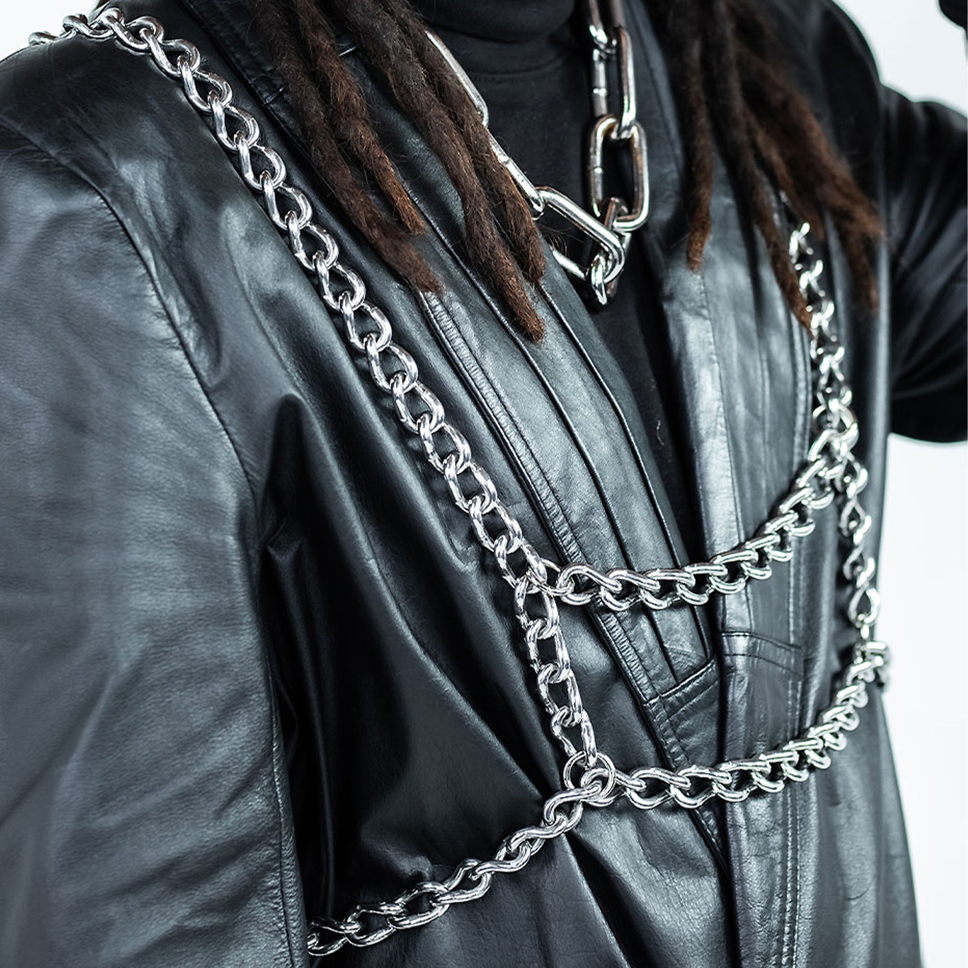 Person wearing a black leather jacket with silver chain details