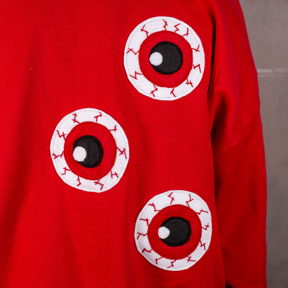 Red sweatshirt with eye designs on a plain background