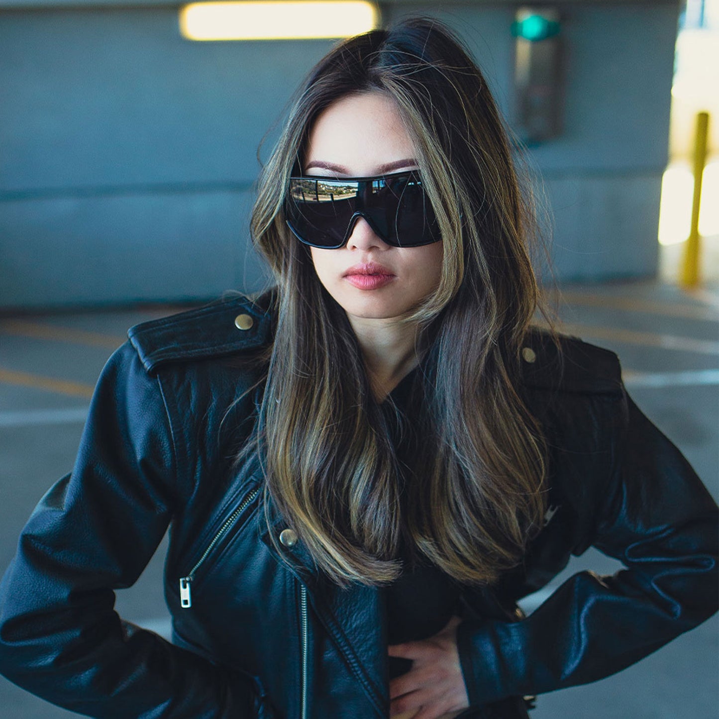 Woman wearing a dark jacket and sunglasses in an urban setting