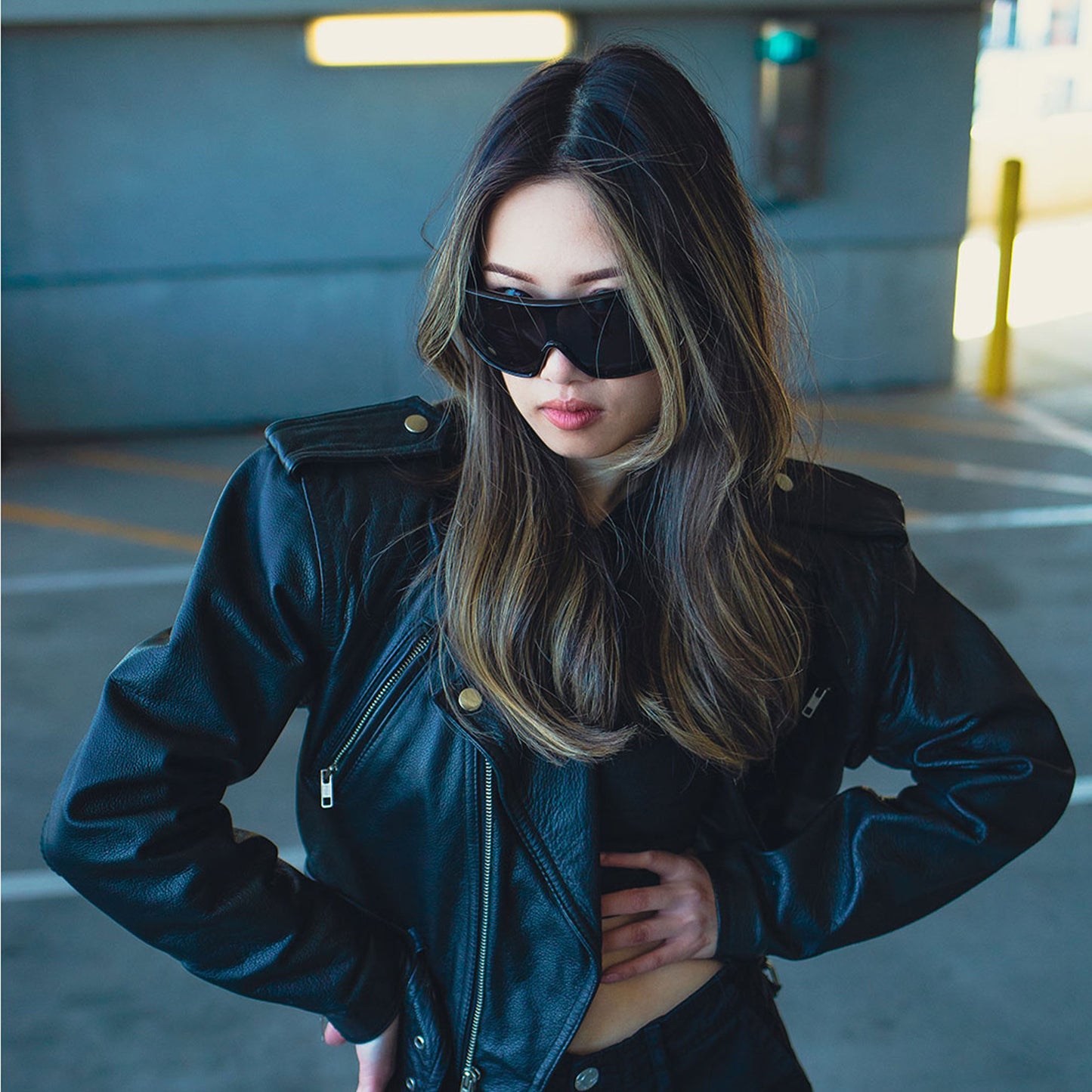 Woman wearing a black leather jacket and sunglasses in an urban setting
